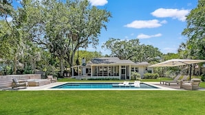 A house with a swimming pool, surrounded by a well-maintained lawn and trees. - 4 BR IOP Beach Rental with Private Pool & Hot Tub (Isle of Palms)