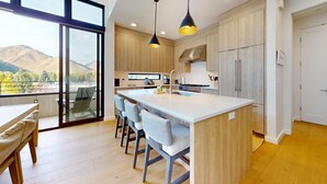Una cocina moderna con una isla central, taburetes de bar y vistas a las montañas.