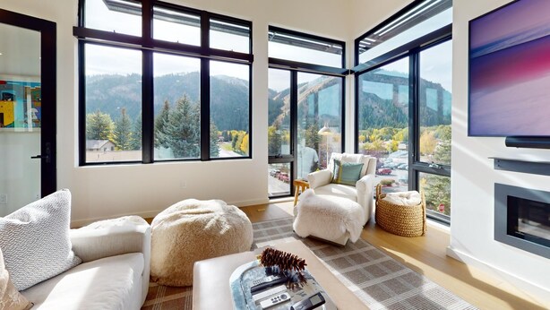Una sala de estar moderna con ventanas amplias, una chimenea y un rincón de asientos acogedor.