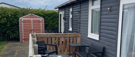 A small house with a porch, a shed, and a table with chairs.
