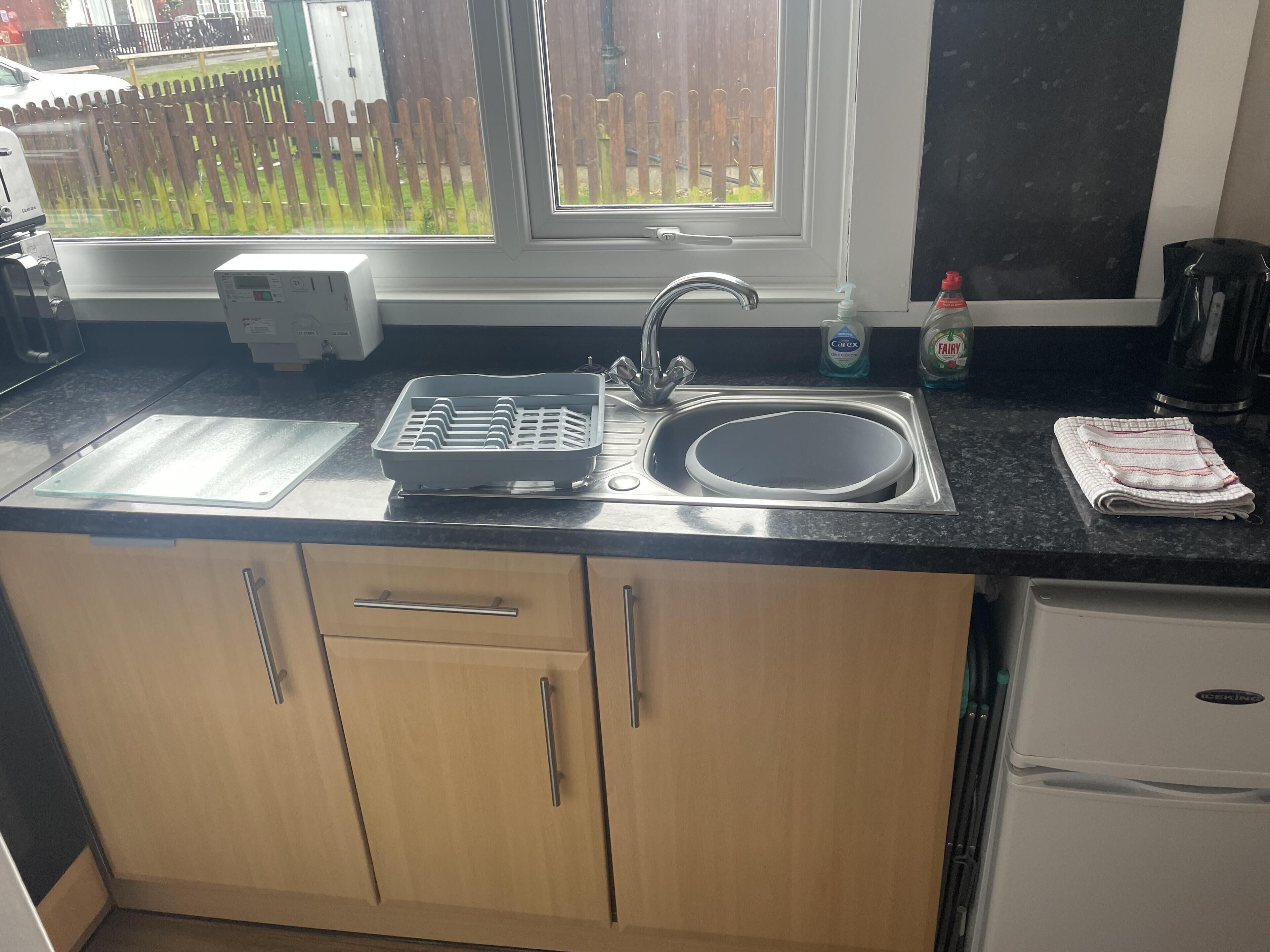 A kitchen with a sink, a toaster, a bread box, and a refrigerator.