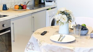 A kitchen with a dining table set for two, featuring a remote control, a plate with cutlery, and a vase with flowers. - Wonderful Holiday Studio in the Trendy Brick Lane (London)