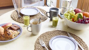 A breakfast setting with croissants, a bowl of fruit, and a coffee pot on a table. - Apartment With Canal View in Broadway Market (London)