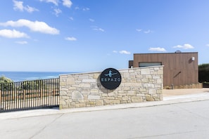 A stone wall with a sign that reads 'ESPAZO' and a view of the ocean. - Espazo (Carballo)