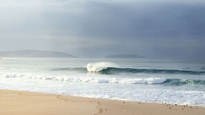 A beach with waves and a distant landmass.