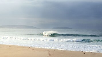 Una playa con olas y una masa de tierra a lo lejos.