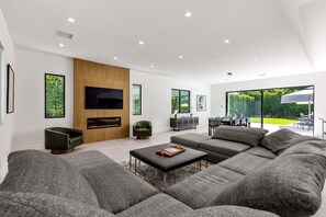 A modern living room with a sectional sofa, a flat-screen TV, and a fireplace. - Villa Moscotto – Luxe Palm Springs Escape (Palm Springs)