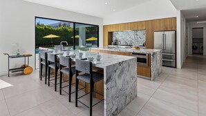Una cocina moderna con una isla de mármol, armarios de madera y un refrigerador de acero inoxidable.