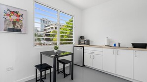 Eine moderne Küche mit weißen Schränken, einer schwarzen Arbeitsplatte, einer Mikrowelle und einem Spülbecken. Ein Fenster bietet Blick auf Gebäude und Bäume.