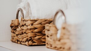 Deux paniers tressés dotés d’anses en métal, chacun contenant une serviette blanche.