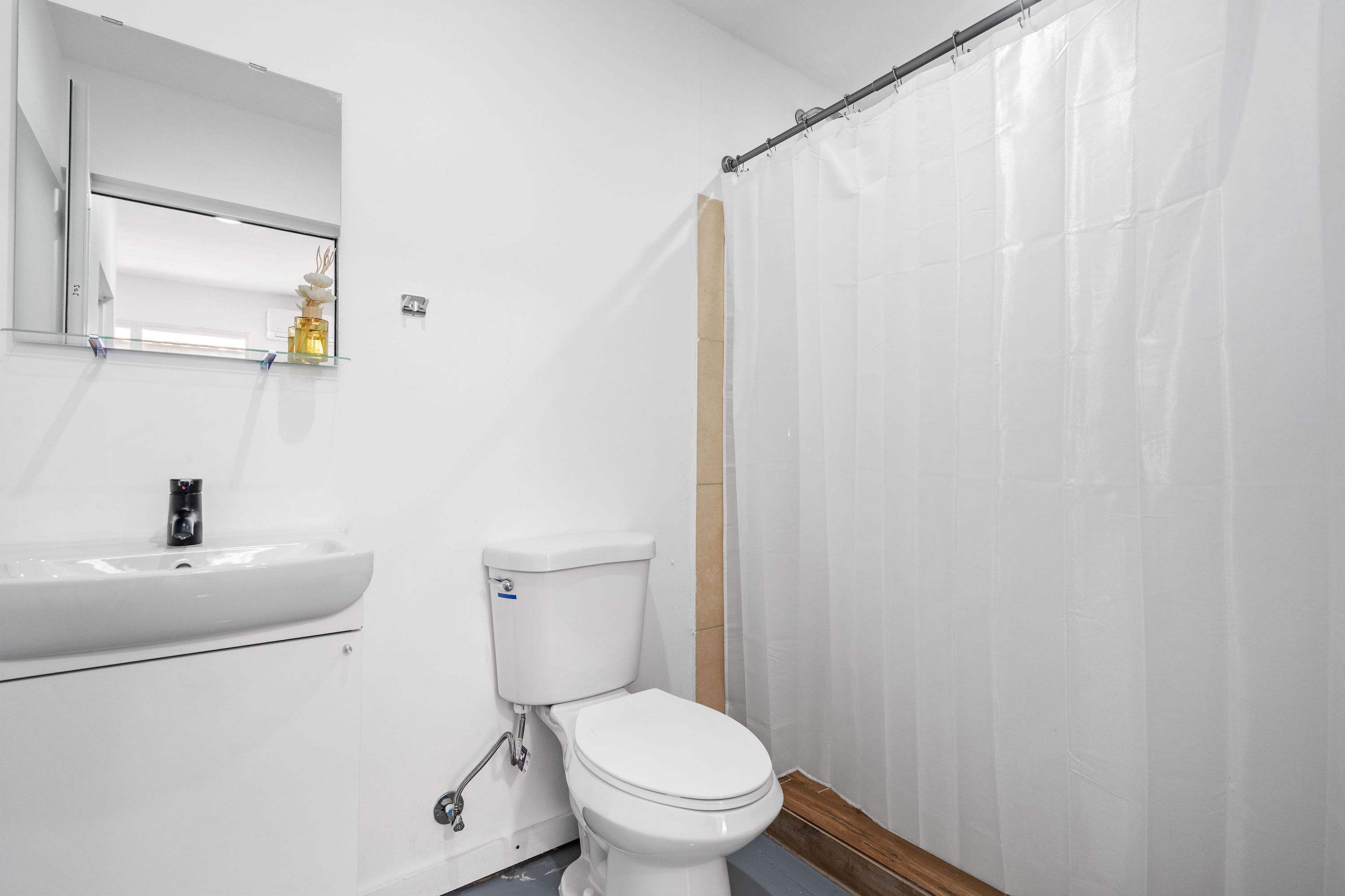 A bathroom with a white sink, toilet, and shower curtain.