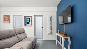 Un salon moderne avec un canapé beige, une table d’appoint en bois et un grand miroir au mur.