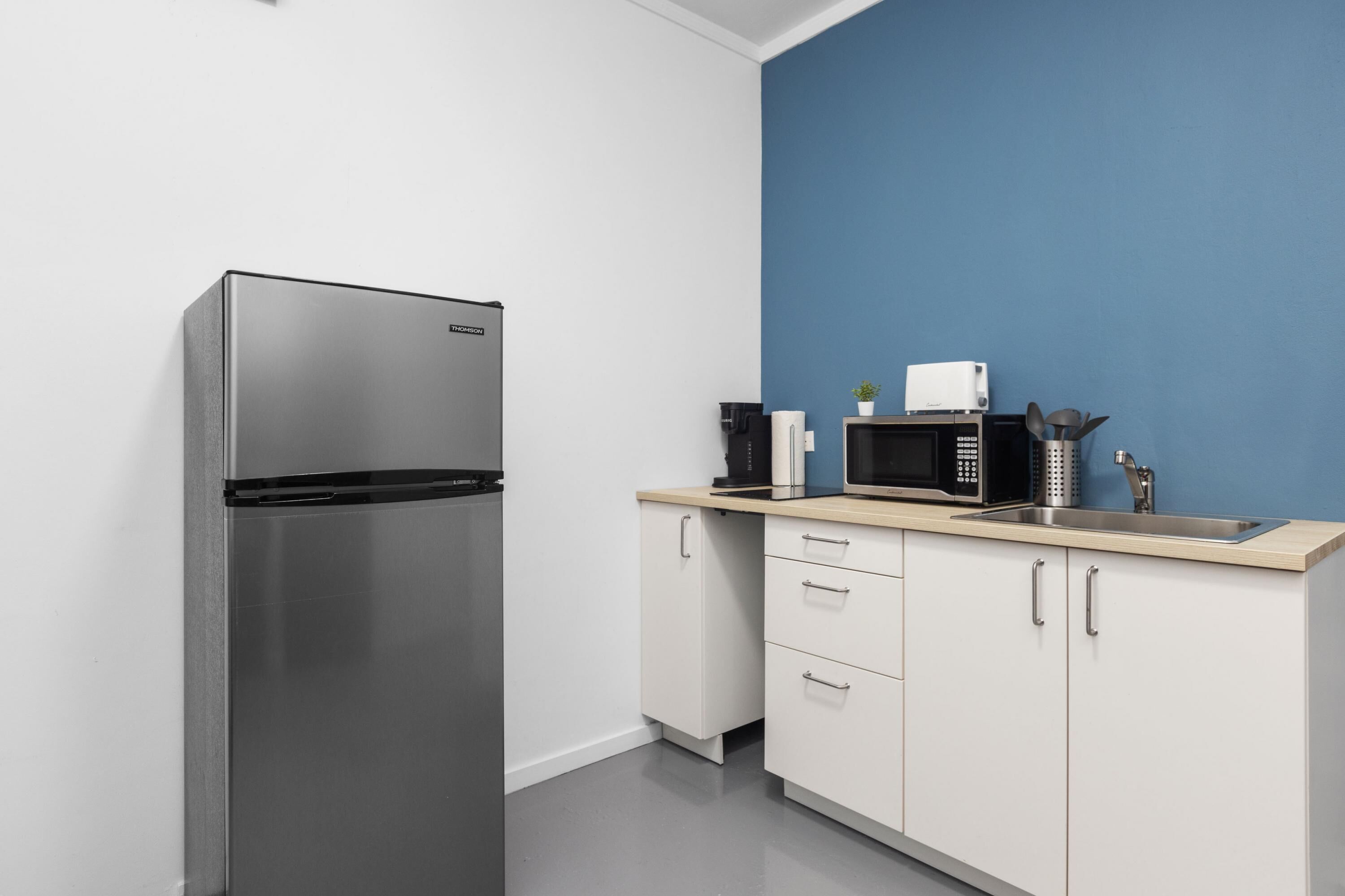 A modern kitchen with a stainless steel refrigerator, a microwave, and a sink.