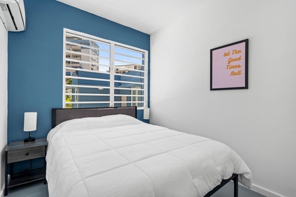 A bedroom with a bed, a nightstand, a wall-mounted air conditioner, a window with blinds, and a motivational poster. - Otium Rentals Ideal Space for Familes Friends (San Juan)