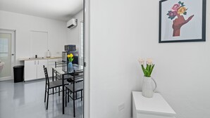 A modern kitchen with white cabinets, a dining table with chairs, and a vase with flowers on a white console table. - Otium Rentals Ideal Space for Familes Friends (San Juan)