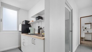 A modern kitchen with white cabinets, a stainless steel sink, and a microwave. - Otium Rentals Spacious Apartment in Condado (San Juan)
