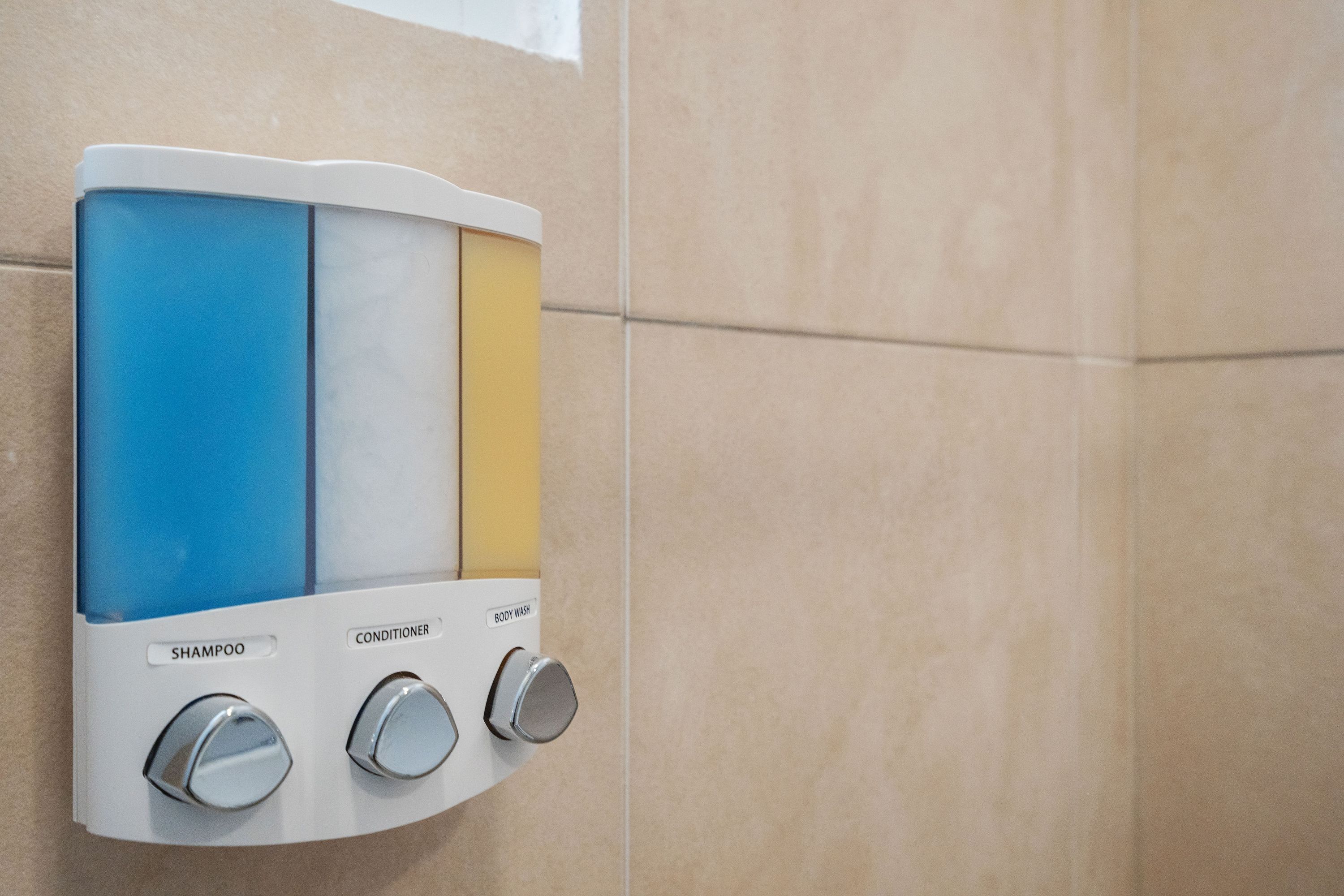 A wall-mounted shower control panel with three sections labeled shampoo, conditioner, and body wash.