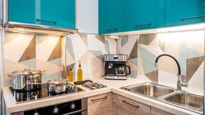 A kitchen with teal cabinets, a coffee maker, a stove, and a sink. - Urban Bloom Oasis - Mini Zen Maison (Kalamata)