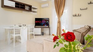 Una sala de estar moderna con televisor, comedor y un sofá con una rosa roja.