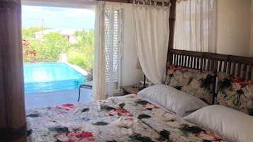 Un dormitorio con cama, mesita de noche y vista a una piscina.