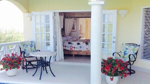 Une terrasse extérieure avec une piscine, un lit et deux chaises agrémentées de plantes en pot.