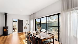 Un intérieur moderne comprenant un coin repas, une cheminée et de grandes fenêtres.