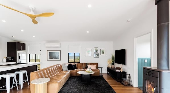 A modern living room with a sofa, coffee table, and a fireplace. - Stunning Cape Woolamai House with Private Pool (Cape Woolamai)