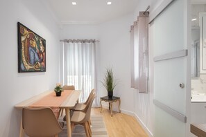 A dining area with a table, chairs, a potted plant, and a painting on the wall. - Athenian Hillside Residence (Athens)