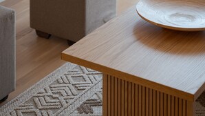 A modern living room with a wooden coffee table, a grey ottoman, and a patterned rug. - Athenian Hillside Residence (Athens)