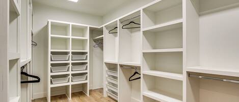 Un vestidor amplio con estantes y espacio para colgar, suelo de madera y un tragaluz.