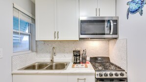 A kitchen with white cabinets, a stainless steel sink, a microwave, a gas stove, and a toaster. - Fort Walton Beach Bungalow w/ Private Hot Tub! (Fort Walton Beach)
