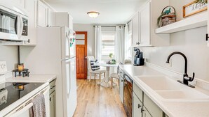 Una cocina moderna con armarios blancos, un grifo negro y piso de madera.