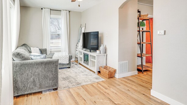 Una sala de estar con un sofá gris, una televisión y un mueble blanco para equipo multimedia.