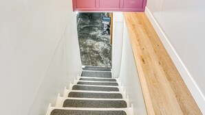 Una escalera con barandilla de madera y techo rosa.