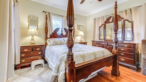 A four-poster bed with a wooden frame and a canopy, flanked by two nightstands with lamps, a dresser with drawers, and a large mirror above the dresser. - Sanford Vacation Rental ~ 1 Mi to Downtown! (Sanford)