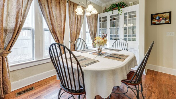 A dining room with a round table, four chairs, a chandelier, and a window with curtains. - Sanford Vacation Rental ~ 1 Mi to Downtown! (Sanford)