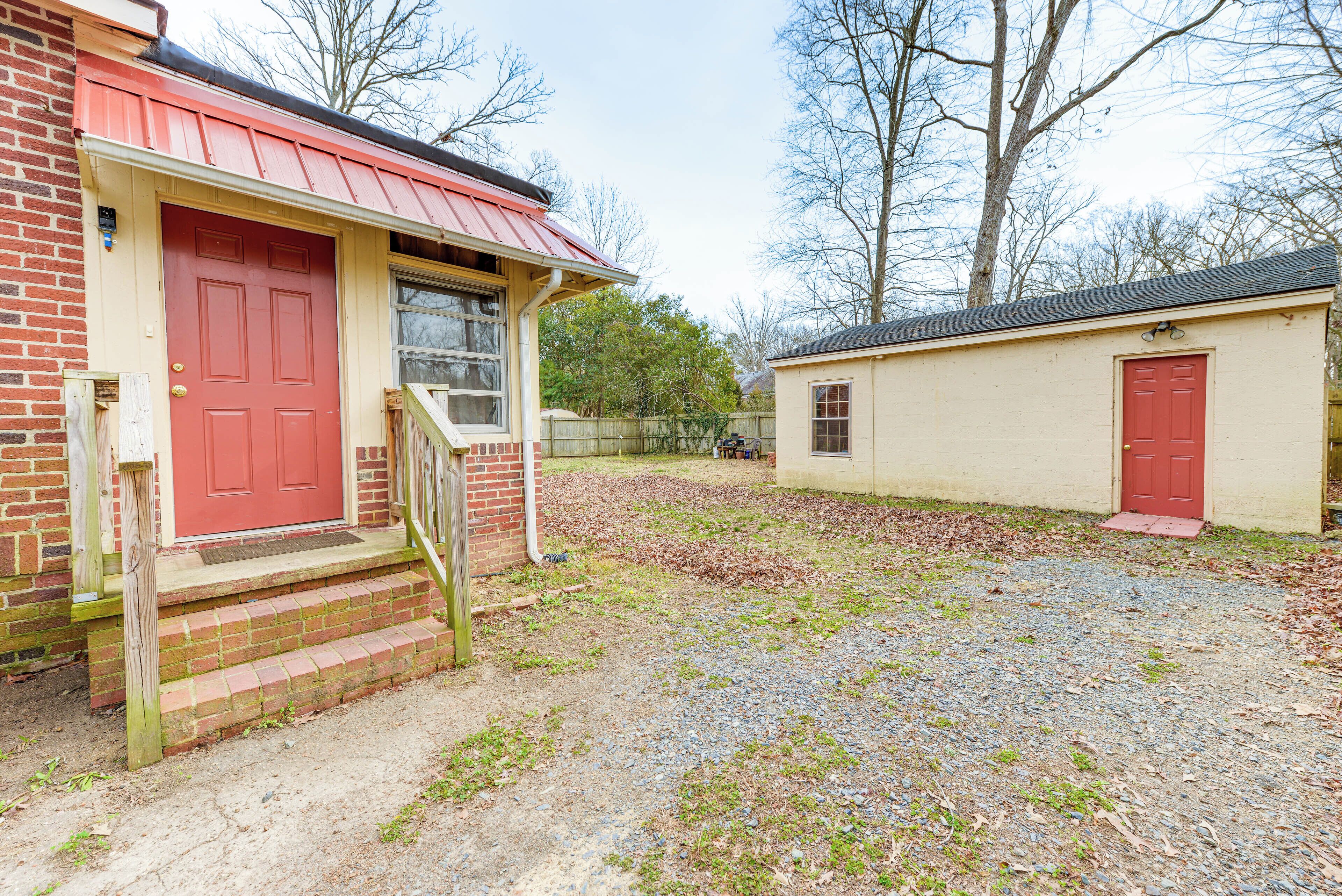 A two-story brick house with a red door and a small porch.