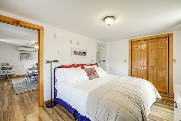 Une chambre à coucher avec un lit, une armoire en bois, un bureau avec une chaise et un petit tapis.