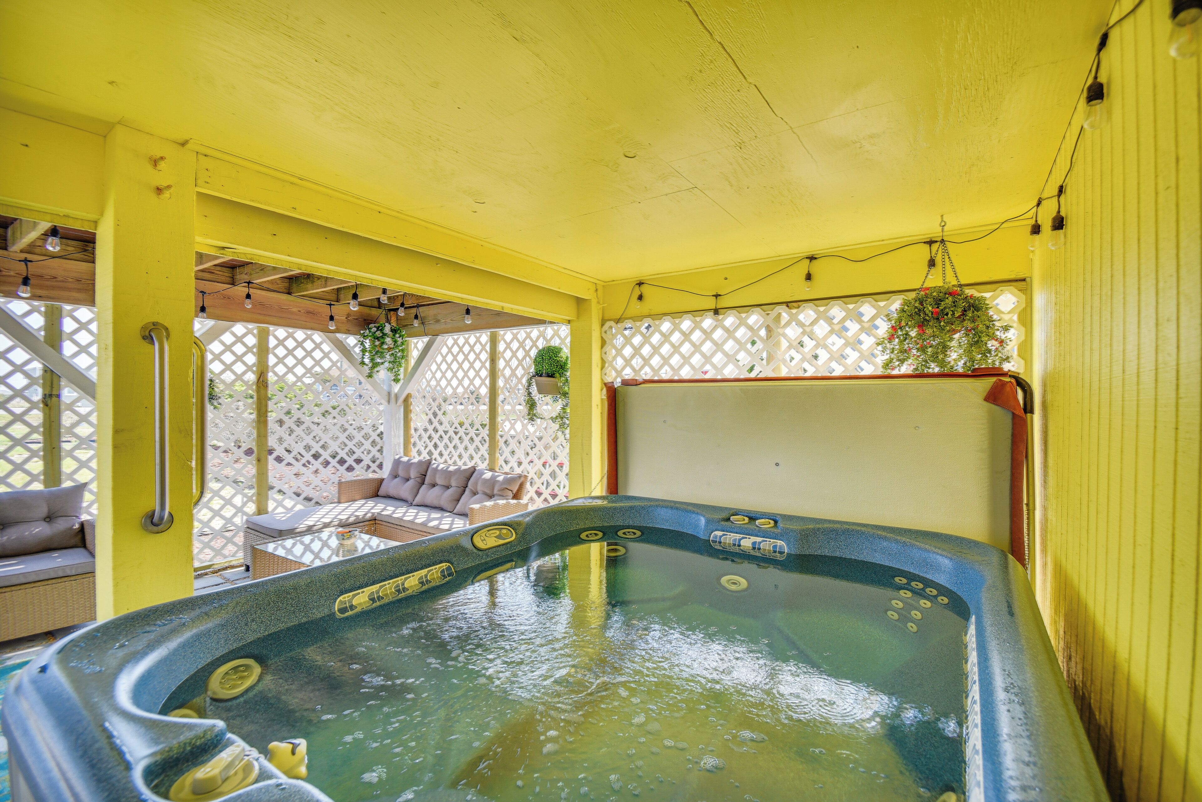 A hot tub with a yellow exterior and a wooden deck area with outdoor seating.