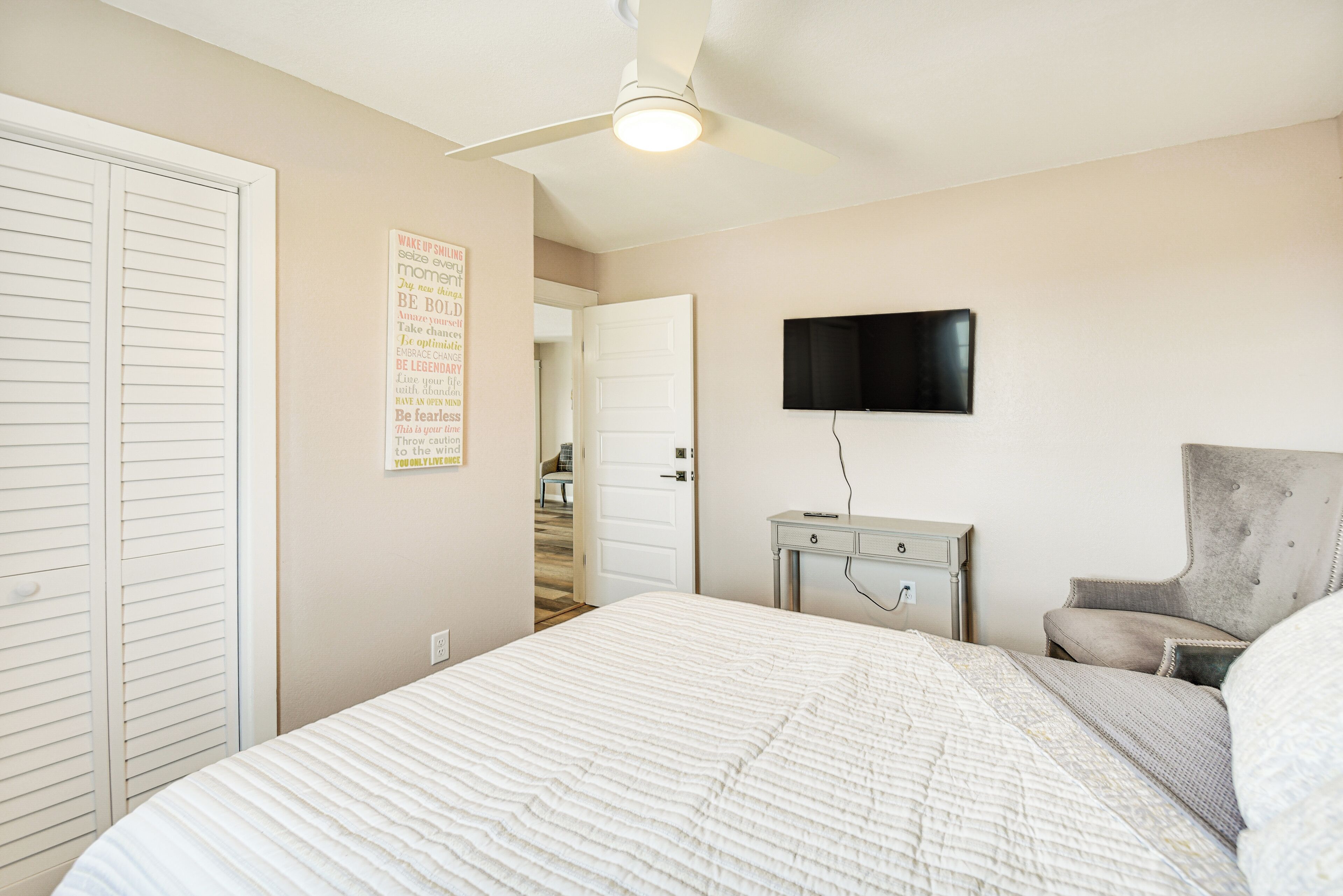 A bedroom with a bed, a desk, a chair, a television, and a closet.