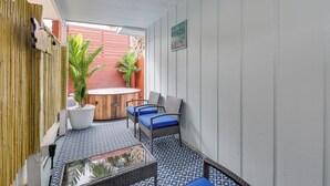 A covered patio area with a table and chairs, a potted plant, and a sign that reads "The Beach Calling".
