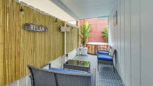 A covered outdoor seating area with bamboo walls, a 'RELAX' sign, and a small table with chairs.