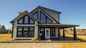 A two-story house with a large front porch, a garage, and a driveway. - Luxury Oceanfront Home in Lunenburg (First South)