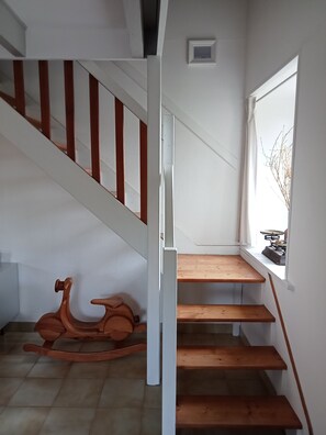 A staircase with wooden steps and a white railing, leading to a landing with a small window and a radiator. - Kermané, Maison Chaleureuse Côte des Légendes - Plage à Pieds (Plouescat)