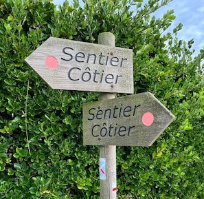 A wooden directional sign with the text "Sentier Côtier" pointing in two directions.