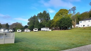 A grassy area with several mobile homes and a building in the background. - Immaculate 2-bed Lodge in Nr Mevagissey (St Austell)