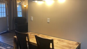 Un comedor con una mesa y sillas de madera, un ventilador de techo y una lámpara fijada a la pared.