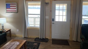 Una habitación acogedora con techo de madera, puerta blanca y vista a un paisaje nevado.