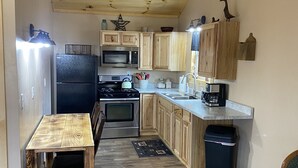 Una cocina compacta con armarios de madera, una mesa de comedor, una estufa y un microondas.