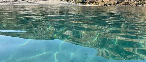 A clear view of a rocky shoreline with a calm body of water reflecting the sky.